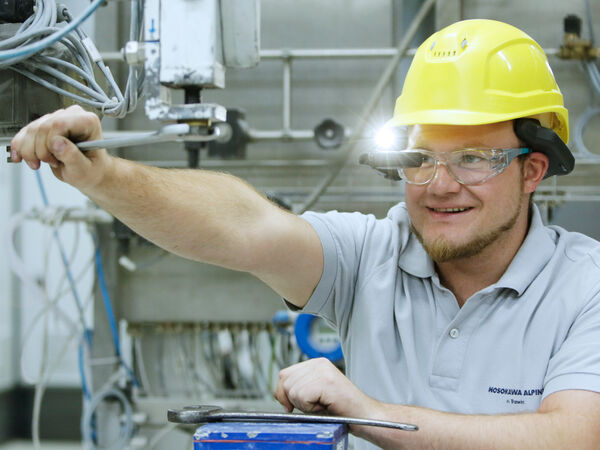 Ein Hosokawa Alpine Mitarbeiter führt Wartungsarbeiten an einer Maschine durch.