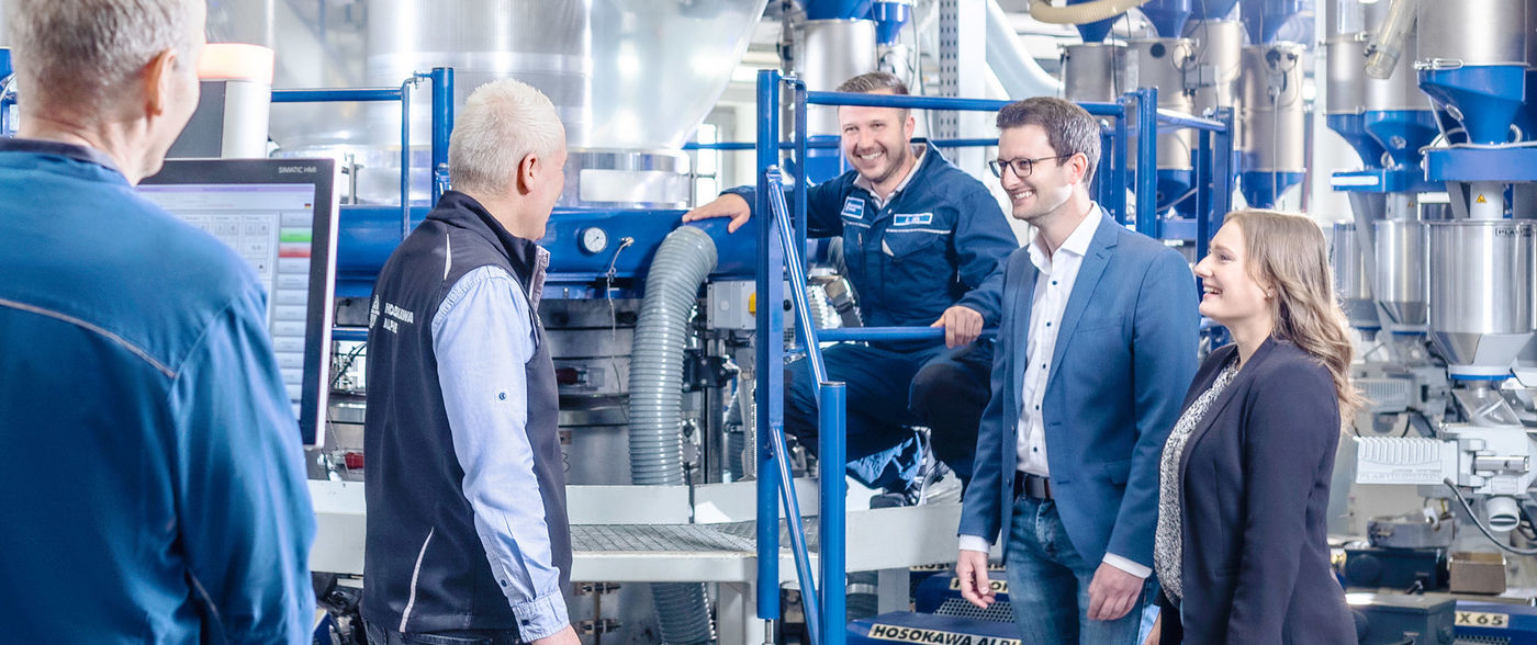 Hosokawa Alpine Mitarbeiter stehen vor einer Blasfolienanlage